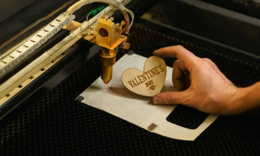 Favism3D: Grabado láser duradero en madera para regalos personalizados y recuerdos que perduran. Mano sosteniendo corazón de madera grabado con láser 'VALENTINE'S DAY', mostrando la durabilidad de nuestros grabados.